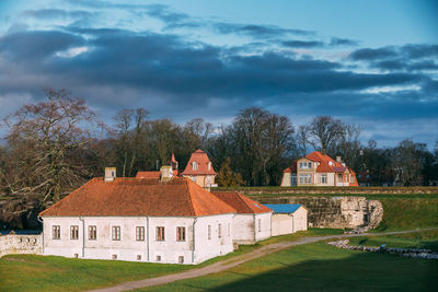 Houses and trees on field against sky