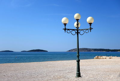 Street lights on beach against clear sky