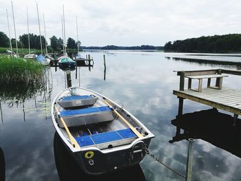 Boats moored at pier on lake against sky