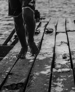 Low section of man walking on footpath by pier