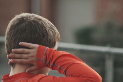 Rear view of boy covering ears