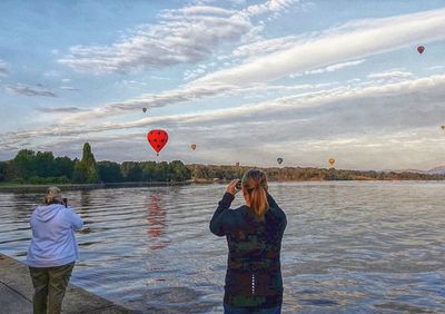 Men standing on hot air balloon against sky