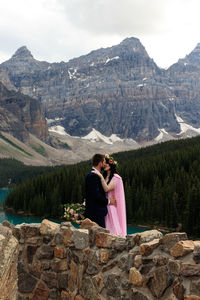 Rear view of couple on rock against mountains