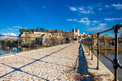 Footpath amidst buildings in town against blue sky