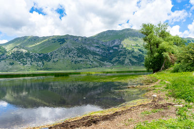 Scenic view of lake by mountains against sky