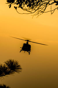 Low angle view of silhouette helicopter against sky during sunset