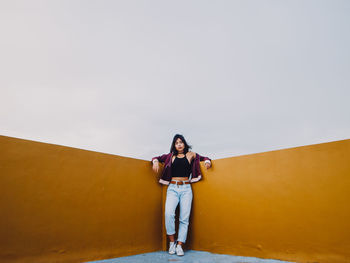 PORTRAIT OF YOUNG WOMAN STANDING AGAINST THE SKY