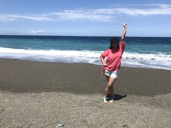 Full length of woman standing on shore at beach against sky