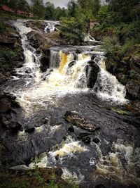 Scenic view of waterfall in forest against sky