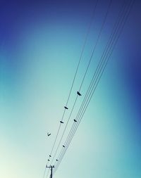 Low angle view of power lines against clear blue sky