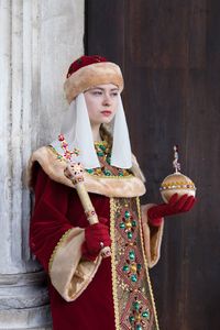 Young woman wearing traditional clothing and religious equipment while standing in church