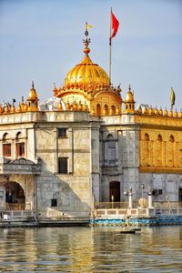 View of temple by river against sky