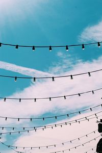 Low angle view of birds perching on cable against sky