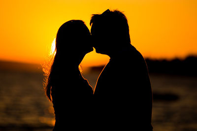 Silhouette couple against orange sky during sunset