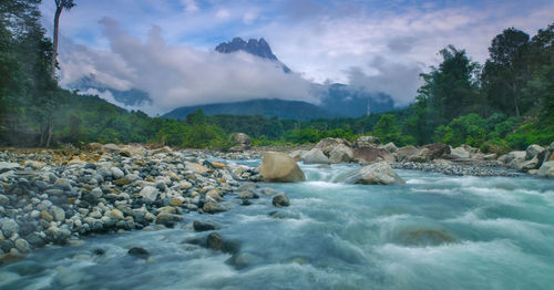 Rocks by river against sky