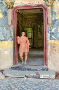 Woman standing against door of building