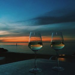Close-up of beer at beach against sky during sunset