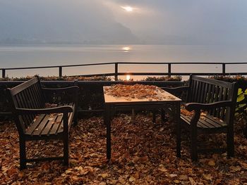 Chairs and table by sea against sky