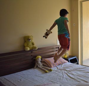 Full length of man with toy on bed at home