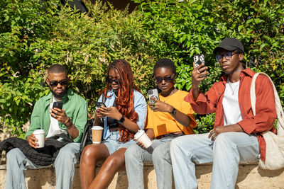 Friends using mobile phone while sitting at park