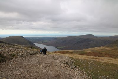 Rear view of men on mountain against sky