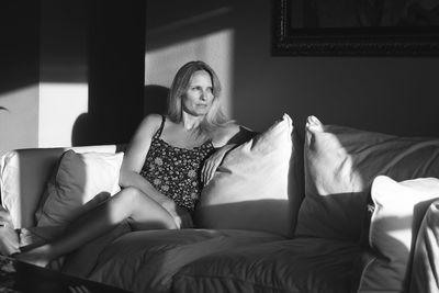 Young woman sitting on sofa at home