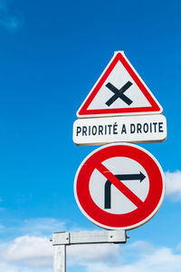 Low angle view of road sign against blue sky