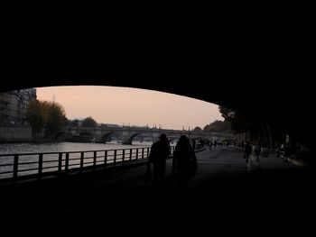 Silhouette people on bridge against sky