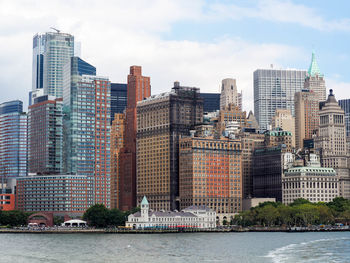 Modern cityscape by river against sky