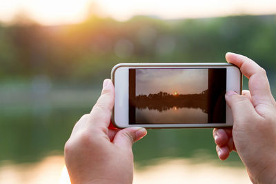 Midsection of man photographing with mobile phone