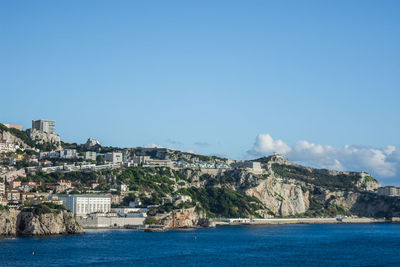 Buildings by sea against blue sky