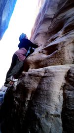 Low angle view of person on rock against sky