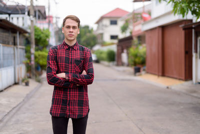 Portrait of young man standing against building