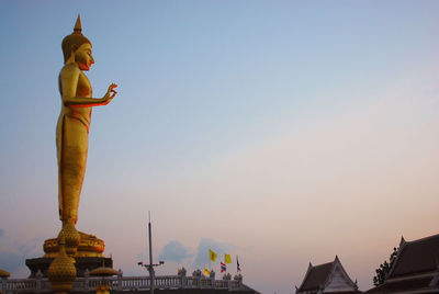 Low angle view of golden buddha statue against sky during sunset