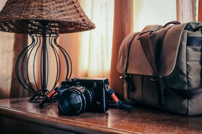 Close-up of camera and bag on table at home