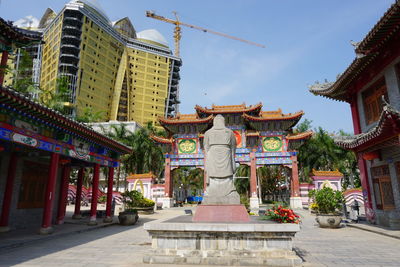 Statue amidst buildings in city against sky