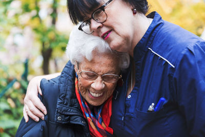 Caretaker embracing senior woman in park