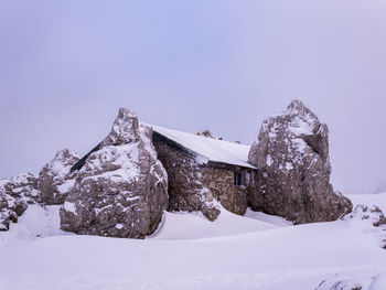 Built structure on snow covered mountain against sky