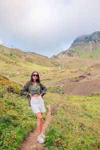 Full length of woman standing on mountain against sky