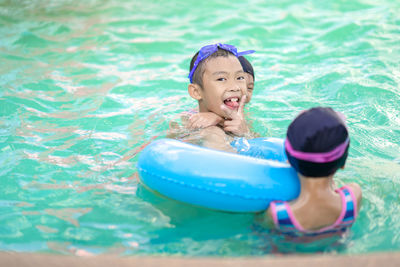 Portrait of happy siblings in swimming pool