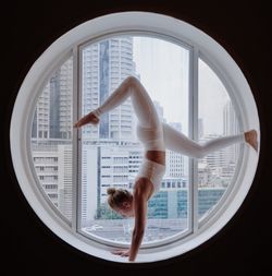 Full length of woman practicing yoga at circular window