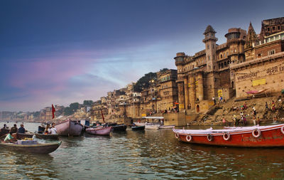 Boats moored in canal against buildings in city