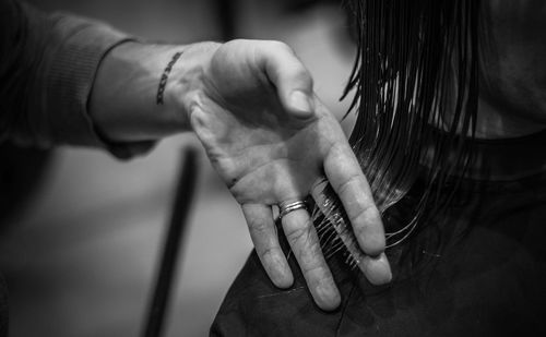 Cropped hand of hairdresser woman touching hair in salon