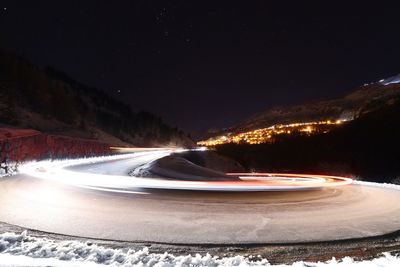 Light trails on street against sky at night during winter