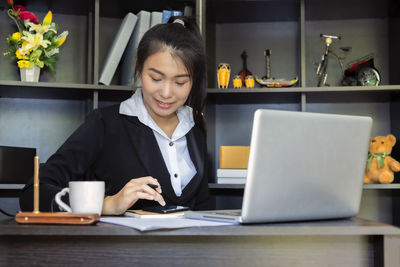 Young woman using laptop on table at home