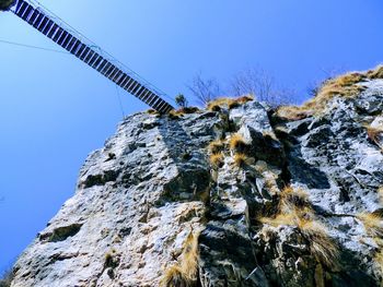 Low angle view of rock formation and tibetan bridge against sky