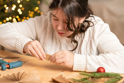 Girl makes christmas tree decorations out of paper with her own hands. step 3