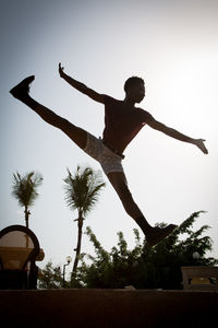 Low angle view of man jumping against clear sky