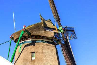 Low angle view of traditional  windmill against clear blue sky