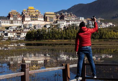 Rear view of woman photographing in city